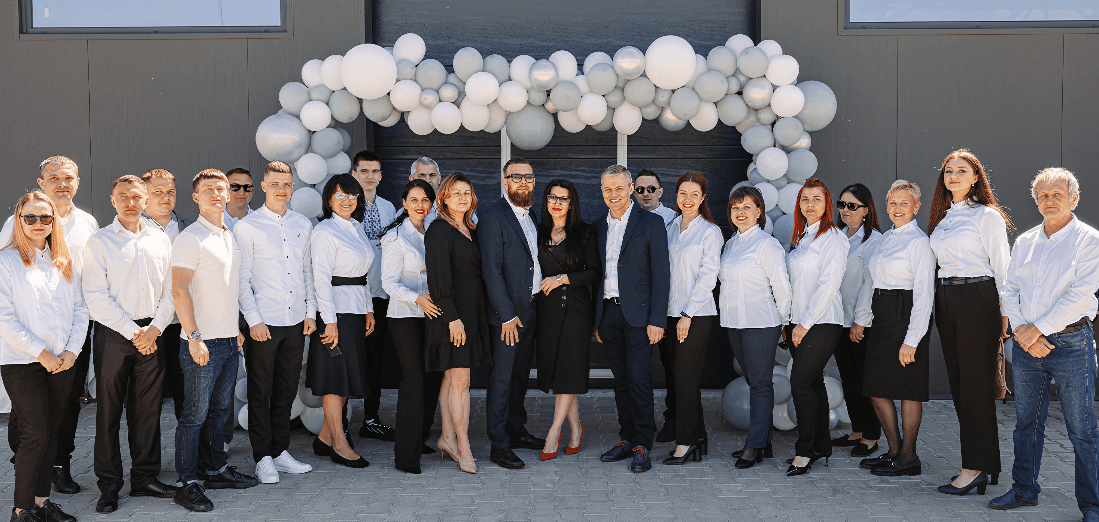 A diverse group of approximately 20 people in business attire pose for a photo.