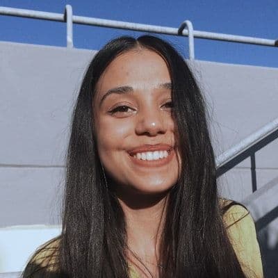 A young woman with long dark hair smiles warmly at the camera.