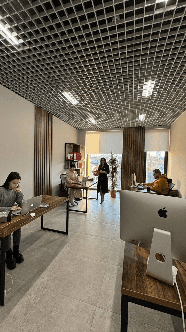 People working in a modern open-plan office with desks and computers.