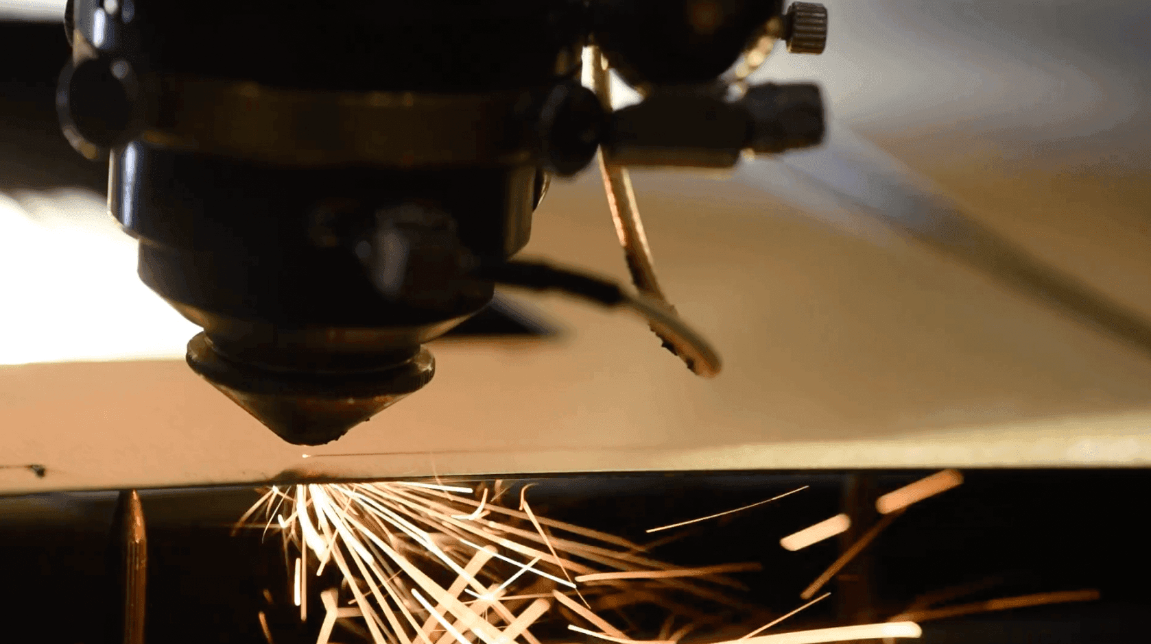 Close-up of a laser cutting machine head with sparks flying.